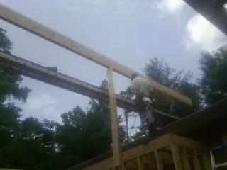 Carpenter setting a ridge beam over a new addition frame — Ice Dam Removal by Roofing Brothers in Le Roy